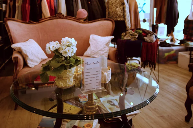 Eine gemütliche Couch im Verkaufsraum mit einem schönen Blumenstrauß und der Kaffee-Preisliste